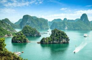 Traditional junk boat sailing through the emerald waters and limestone karsts of Ha Long Bay, Vietnam