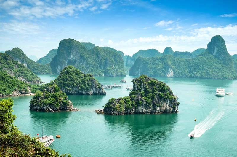 Traditional junk boat sailing through the emerald waters and limestone karsts of Ha Long Bay, Vietnam