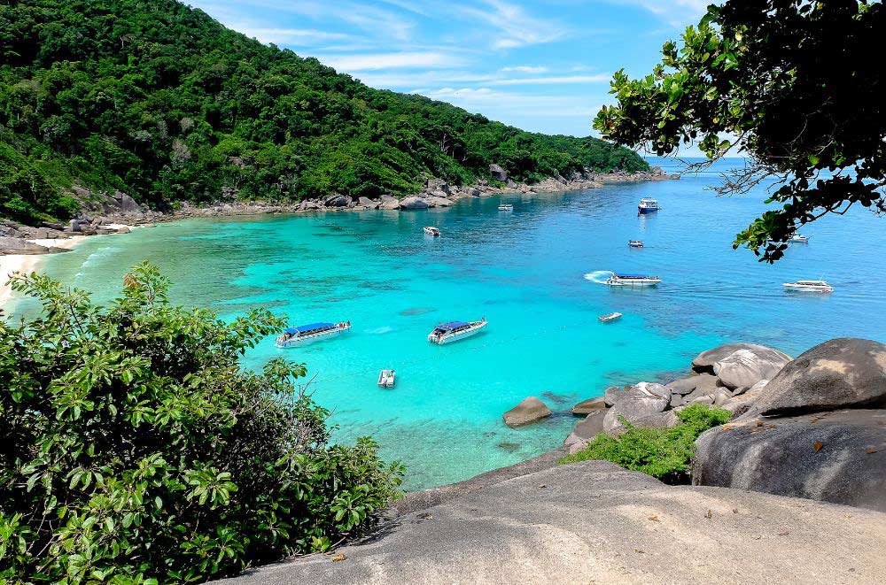 Longtail boats anchored on the turquoise waters of Patong Beach in Phuket, Thailand
