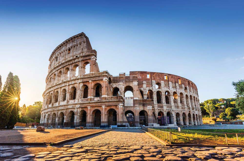 Sunset view of the Colosseum in Rome, Italy, with tourists walking nearby