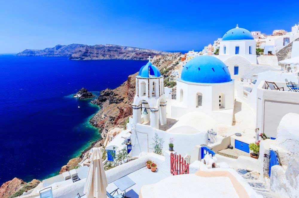 Whitewashed buildings with blue domes overlooking the Aegean Sea in Oia, Santorin